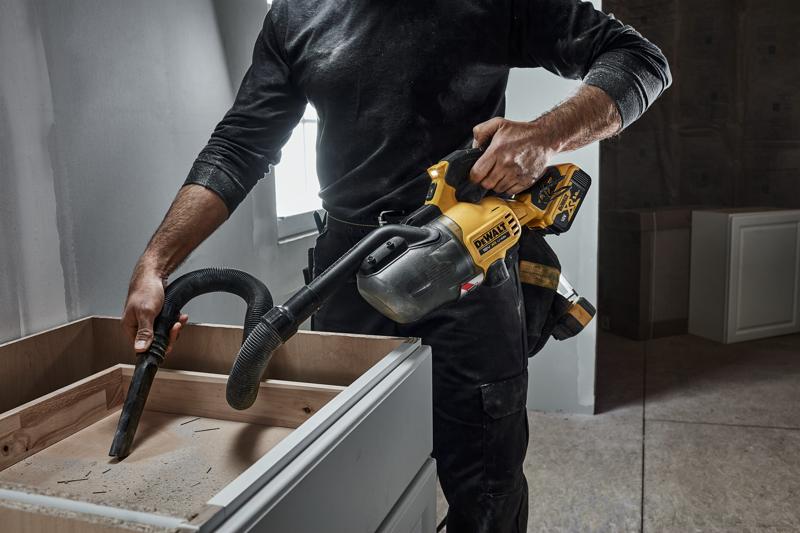 A CARPENTER USING A DCV501L 18V XR L-CLASS STICK VAC TO CLEAN A KITCHEN CABINET